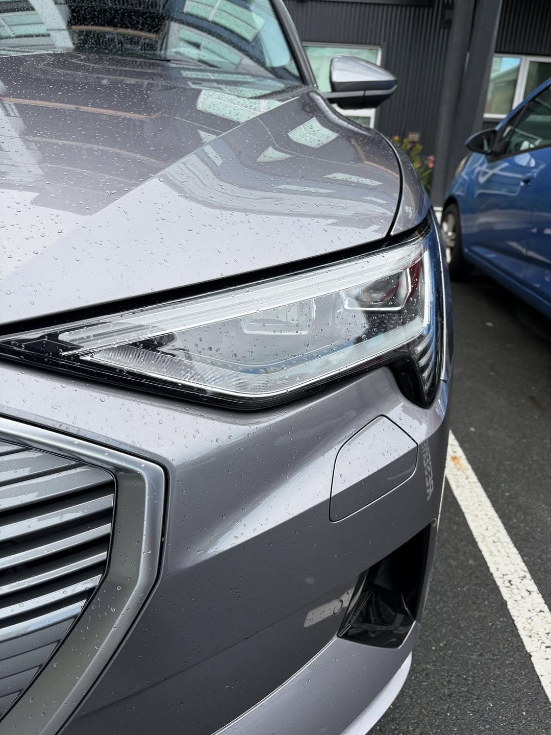 Detailed car headlight with rain droplets showcasing premium auto detailing finish